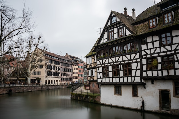 Río rodeado de coloridos edificios y vegetación bajo un cielo nublado en Estrasburgo en Francia