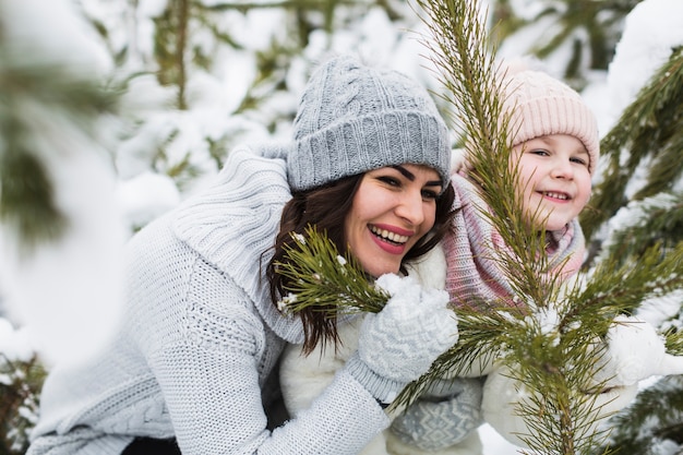 Risa de mujer y niña cerca de picea