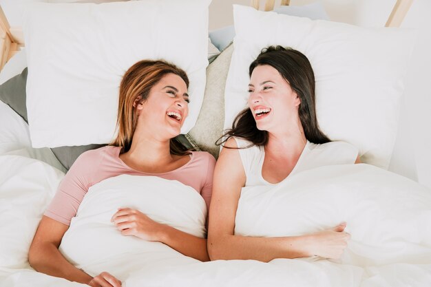 Risas mujeres acostadas en la cama