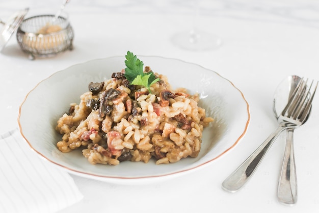 Risotto de arroz con champiñones sobre plato de cerámica blanca.