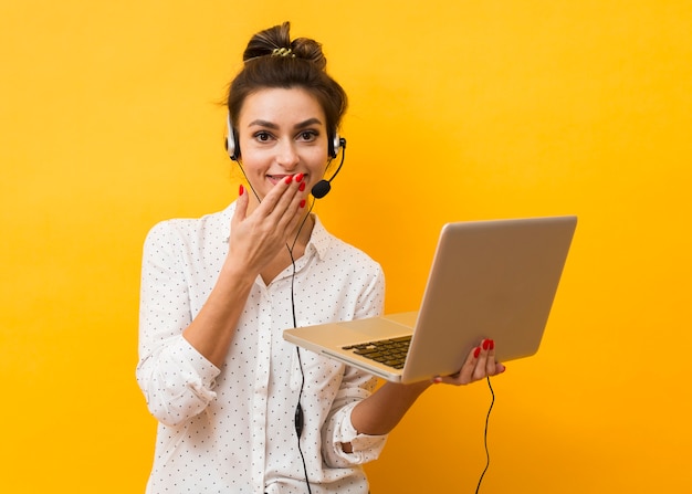 Foto gratuita risueña mujer usando auriculares y sosteniendo portátil