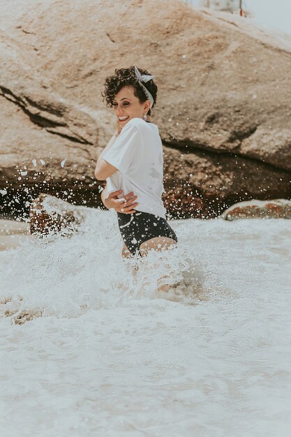 Rizado pelo corto jugando con las olas en la orilla del mar.