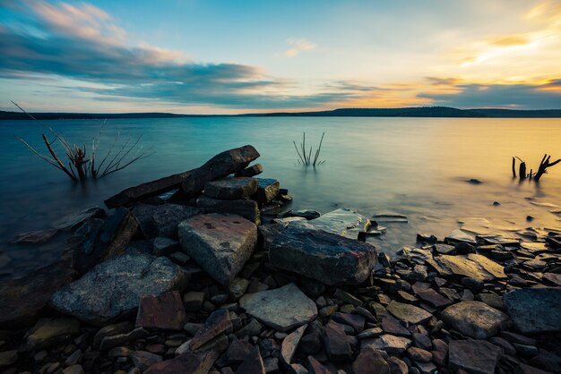 Rocas en el cuerpo del lago con un hermoso paisaje al atardecer detrás