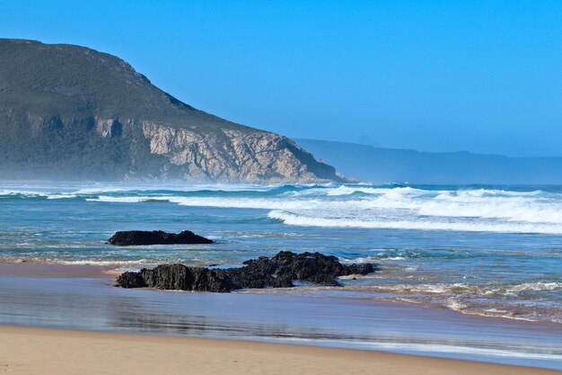 Rocas en la playa junto al hermoso océano con las montañas