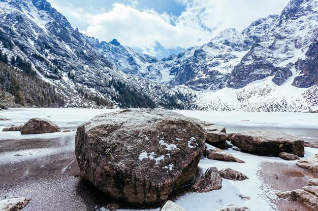 Rocas sobre el lago con montañas en invierno