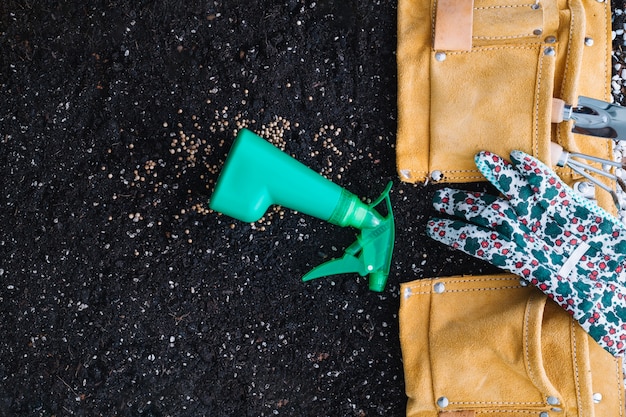 Rocíe la botella cerca de la bolsa con herramientas de jardinería