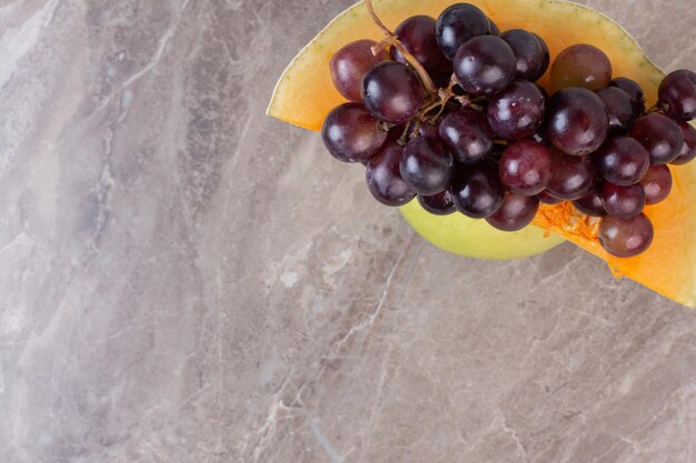 Foto gratuita una rodaja de calabaza y uvas en la superficie de mármol.