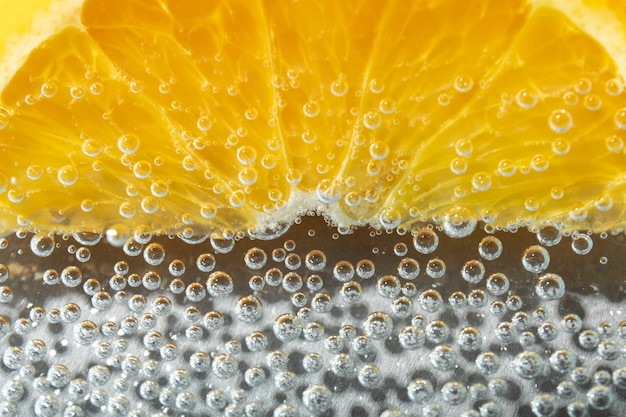 Rodaja de naranja plana y agua con gas