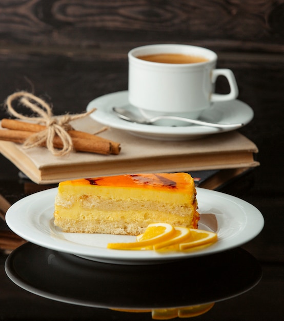 Una rodaja de tarta de limón con una taza de té.