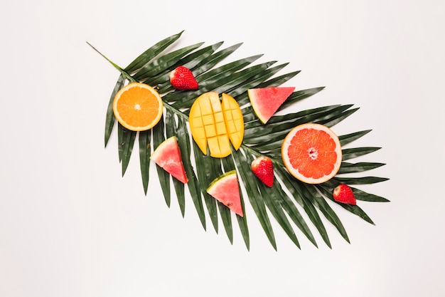 Foto gratuita rodajas de apetitoso sandía roja fresa naranja mango en hoja de palma