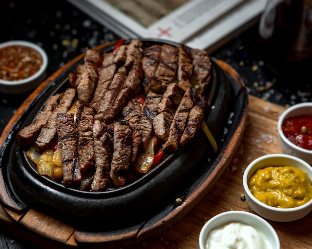 Rodajas de carne frita con cebolla frita sobre la plancha de madera