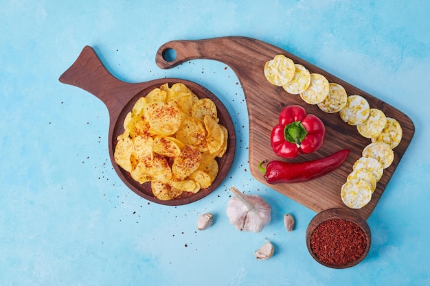 Rodajas de chile rojo y pimiento morrón en bandeja de madera servido con patatas fritas. Foto de alta calidad