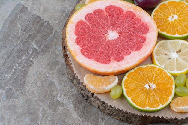 Foto gratuita rodajas de cítricos y uvas en pieza de madera.