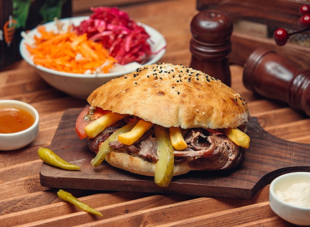 rodajas de cordero doner con papas fritas, pepino en vinagre, tomate en pan de pita