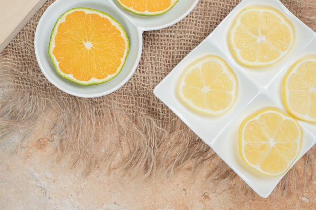 Rodajas frescas de naranja y limón en varios platos.