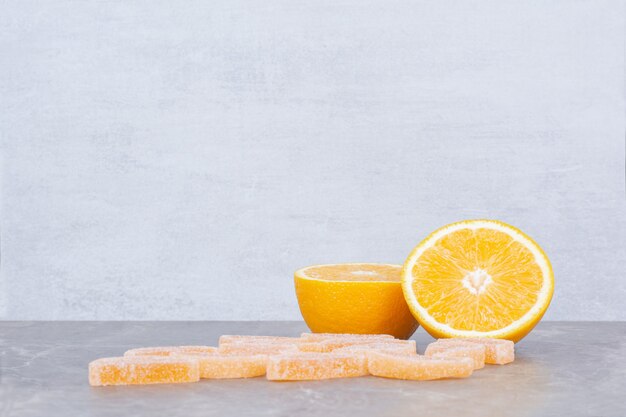 Rodajas frescas de naranja con mermeladas dulces sobre fondo de mármol.