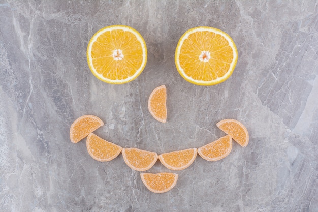 Rodajas frescas de naranja con mermeladas dulces sobre fondo de mármol.