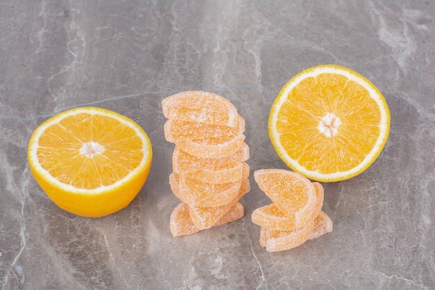 Rodajas frescas de naranja con mermeladas dulces sobre fondo de mármol.