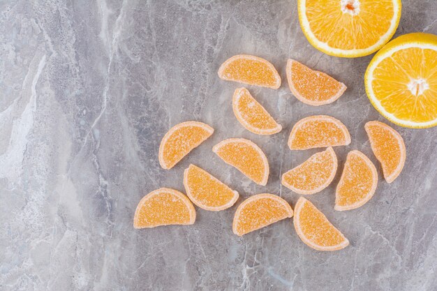 Rodajas frescas de naranja con mermeladas dulces sobre fondo de mármol.