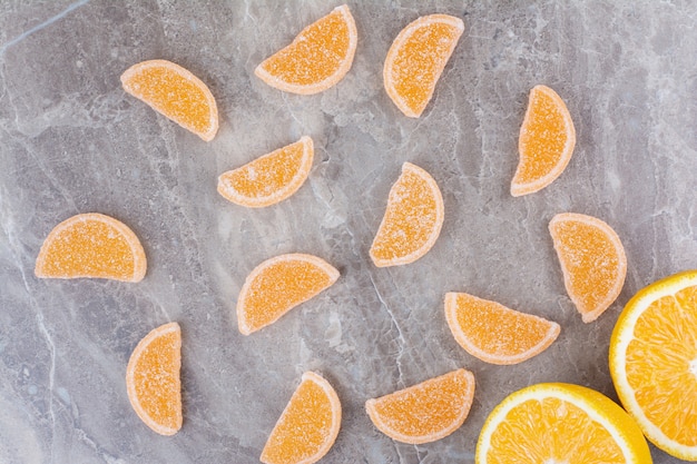 Rodajas frescas de naranja con mermeladas dulces sobre fondo de mármol.