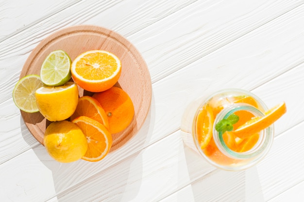 Rodajas de fruta con botella de limonada.