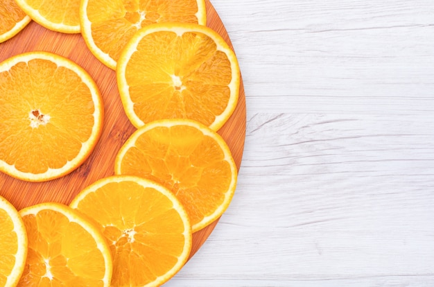 Rodajas de fruta naranja en la vista superior de la tabla de cortar de madera con espacio de copia