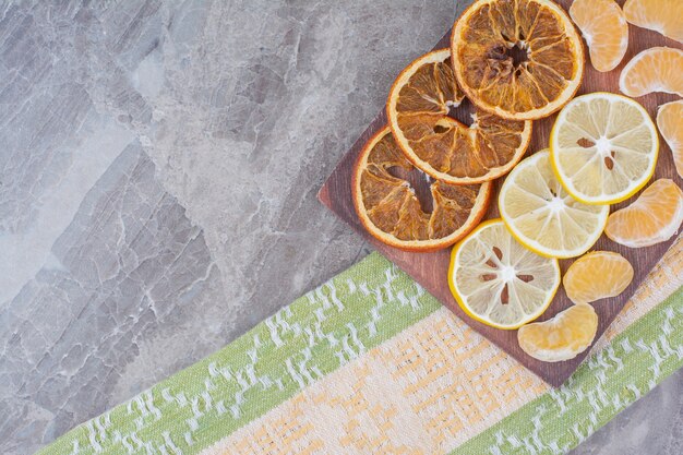 Rodajas de frutas cítricas en tablero de madera con mantel.