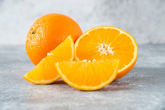 Rodajas y frutas de naranja jugosas enteras en la mesa de piedra.