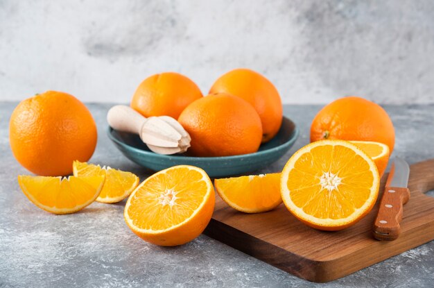 Rodajas de frutas de naranja con naranjas enteras sobre una tabla de madera.