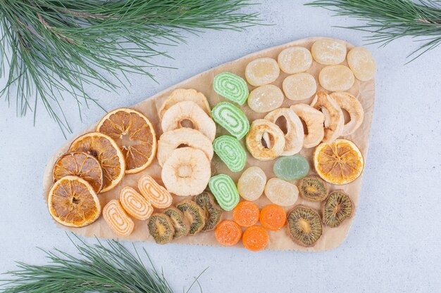 Rodajas de frutos secos y dulces de mermelada sobre plancha de madera.