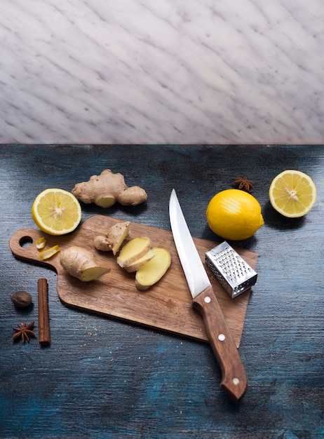 Rodajas de jengibre en tablero de madera con limón en la mesa