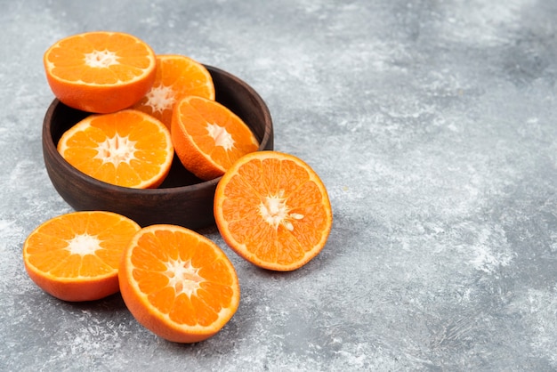 Rodajas de jugosas frutas naranjas frescas en un cuenco de madera.