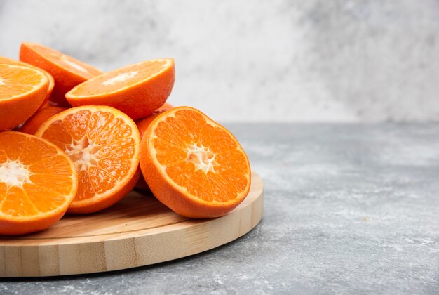 Rodajas de jugosas frutas naranjas frescas en una placa de madera.