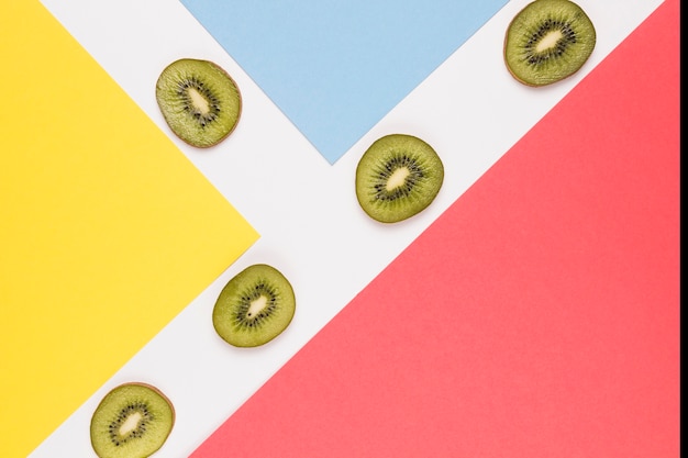 Foto gratuita rodajas de kiwi jugoso en superficie multicolor