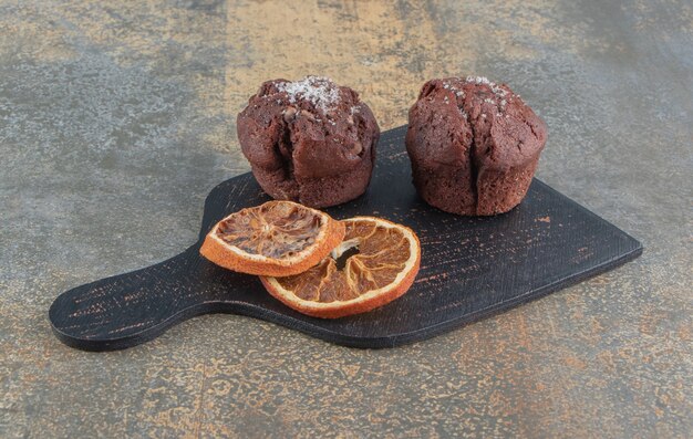 Rodajas de limón seco y cupcakes de chocolate sobre tabla de madera