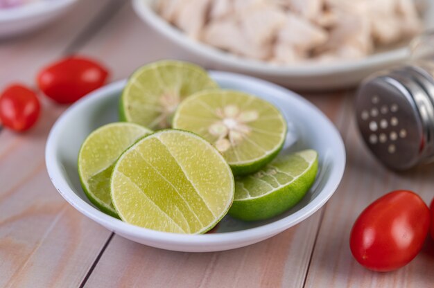 Rodajas de limón en una taza y tomates en una mesa de madera.