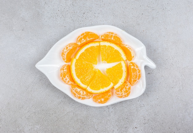 Rodajas de mandarina y naranja en un plato blanco.