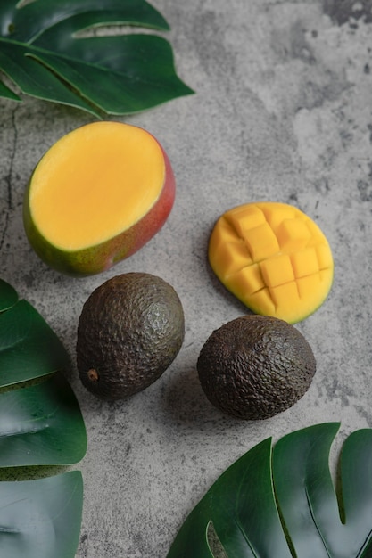 Rodajas de mango y aguacate maduros sobre superficie de mármol.