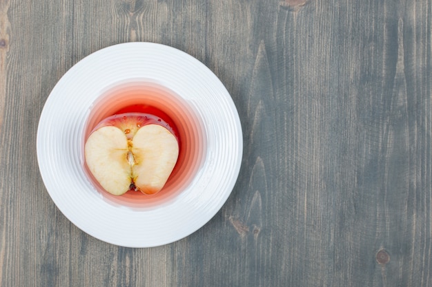 Foto gratuita rodajas de manzana roja en jugo en una placa blanca.