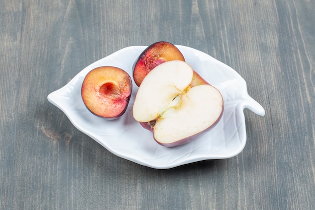 Foto gratuita rodajas de manzana roja con rodajas de ciruela en una placa blanca.