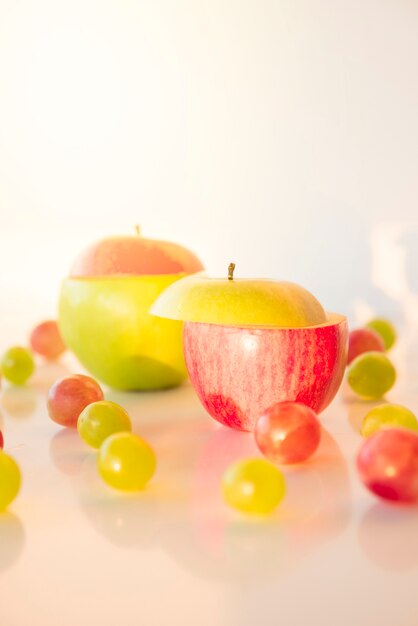 Rodajas de manzana roja y verde con uvas sobre fondo blanco