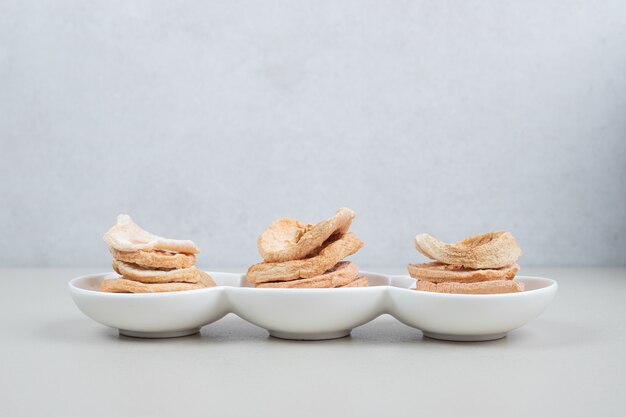 Rodajas de manzana secas en la placa blanca.