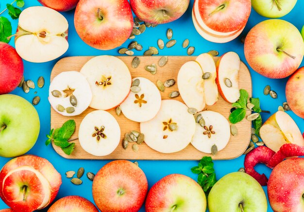 Rodajas de manzana; Semillas de calabaza y hojas de menta contra el fondo azul