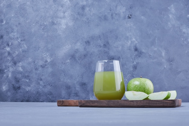 Rodajas de manzana verde con un vaso de jugo.