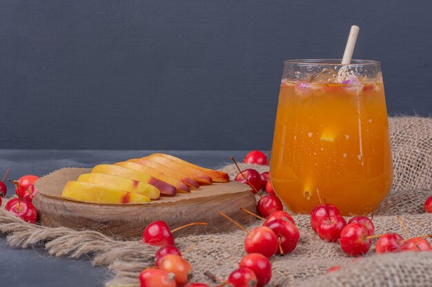 Rodajas de melocotón, cerezas y vaso de jugo de fruta en azul.