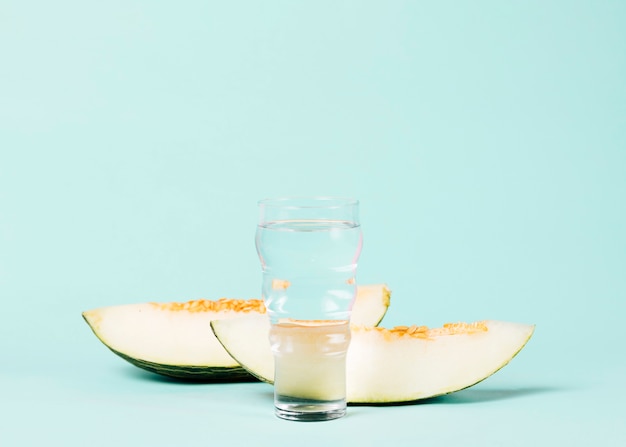 Foto gratuita rodajas de melón con un vaso de agua