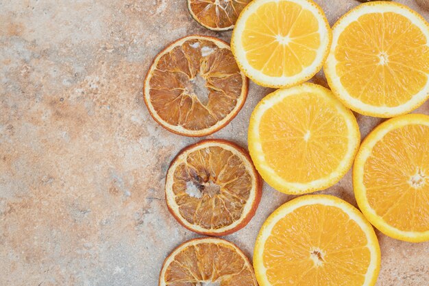 Rodajas de naranja frescas y secas sobre fondo de mármol.