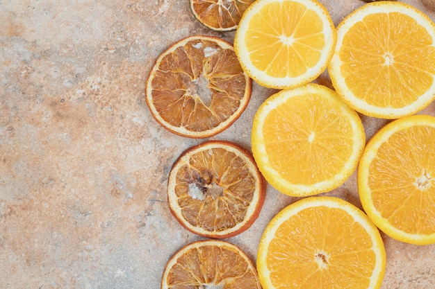 Rodajas de naranja frescas y secas sobre fondo de mármol.