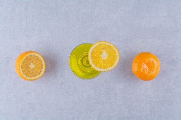 Rodajas de naranja y jugo de frutas sobre mesa de mármol.