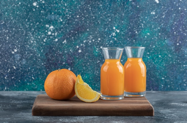 Foto gratuita rodajas de naranja y jugo sobre tabla de madera.